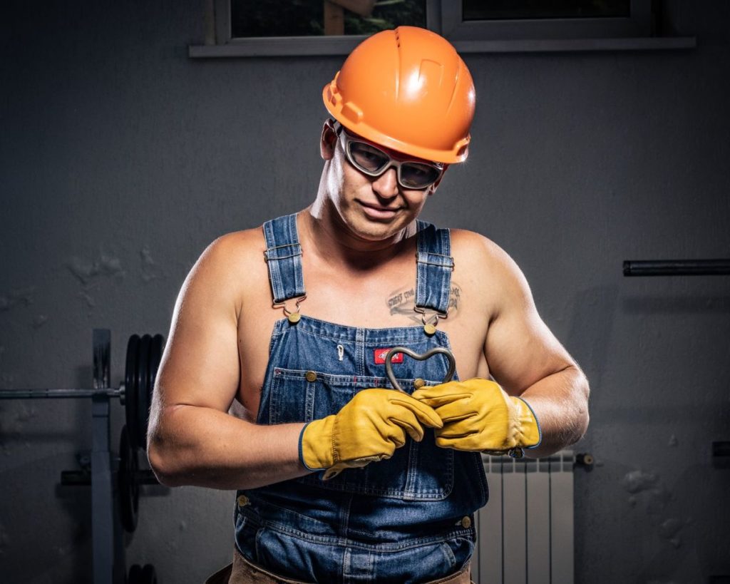 Plumber in a hard hat checking a fitting