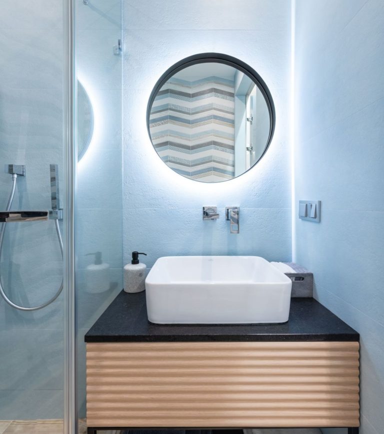 Blue bathroom with a round mirror and a sink