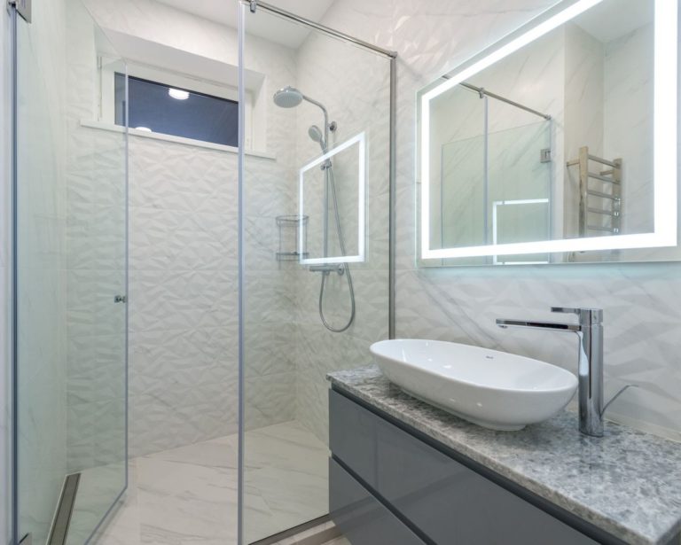 Bathroom with a glass shower and a backlit mirror